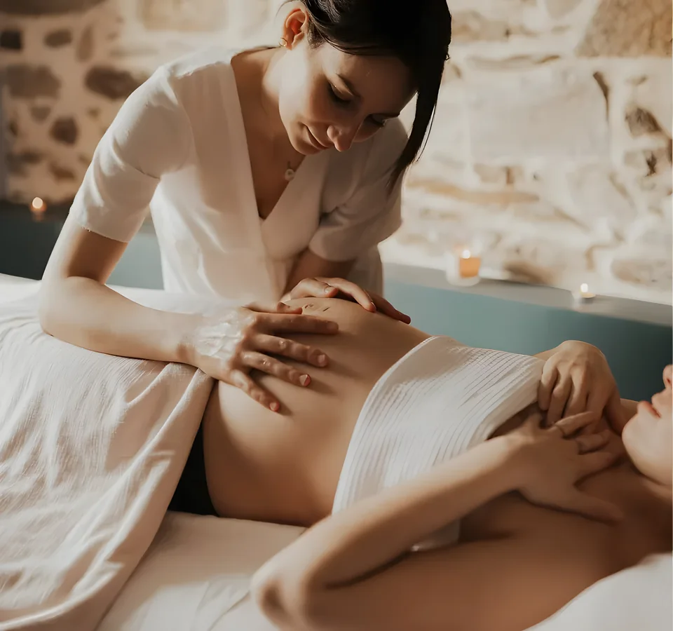 Massage prénatal du ventre d’une femme enceinte dans une salle de soin tamisée