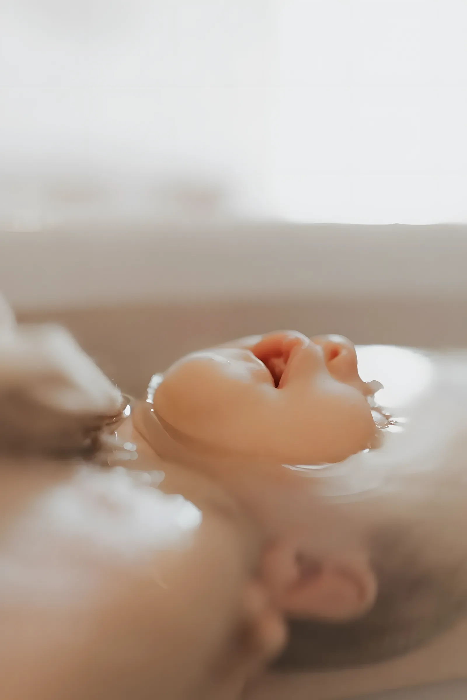 Visage apaisé d’un nouveau-né flottant dans l’eau tiède du Bain d’Accueil du Nouveau-né®